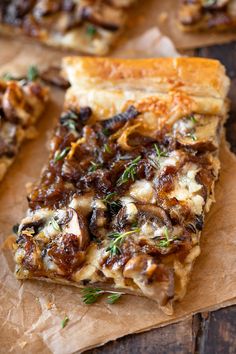 a piece of pizza with mushrooms and cheese on it sitting on top of brown paper