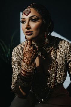 a woman with her hands on her face and jewelry around her neck, posing for the camera