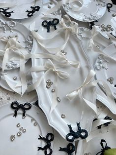 white plates with black bows and pearls on them are arranged in a pattern, including scissors