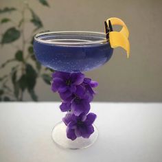 purple flowers in a glass vase with a yellow bird decoration on the top and bottom