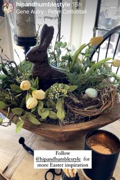 a table topped with a bowl filled with flowers and an animal figurine sitting on top of it