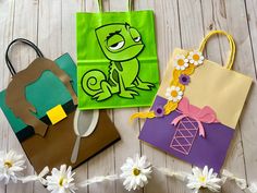 three paper bags with designs on them sitting on a table next to daisies and flowers