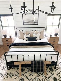 a bedroom with a bed, dressers and chandelier hanging from the ceiling