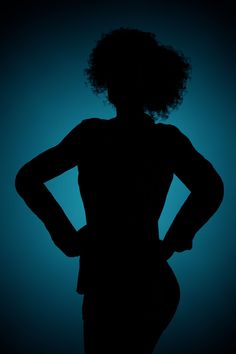 the silhouette of a woman with her hands on her hips, against a blue background