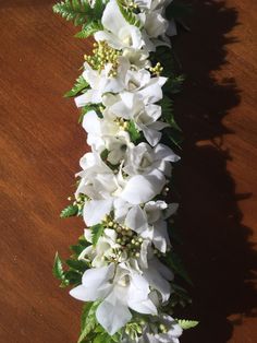 white flowers and green leaves on a wooden table