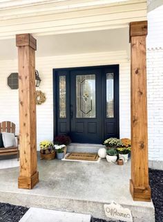 the front porch is decorated with potted flowers and wreaths on either side of the door