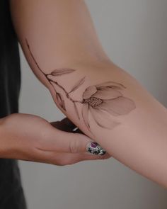 a woman's arm with a flower tattoo on it