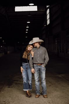 a man and woman are standing in an empty warehouse with cowboy hats on their heads