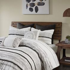 a bed with white and black comforter in a bedroom next to a wooden headboard