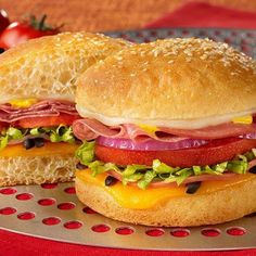 a sandwich with ham, cheese and lettuce sitting on a plate next to tomatoes