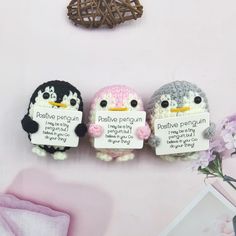 three small stuffed penguins are hanging on the wall with signs attached to them that say positive penguinies