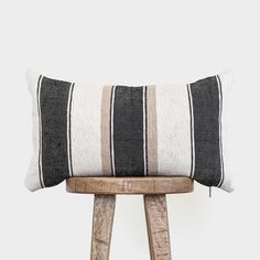 a black and white striped pillow sitting on top of a wooden stool