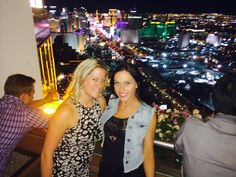 two women standing next to each other in front of a cityscape at night