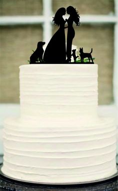 a white cake with a black silhouette of two people and a dog on top that is standing in front of a window