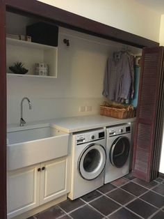 a washer and dryer in a small room with open cabinets on the wall