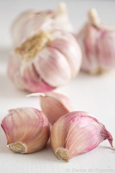 three garlics and two heads on a white surface