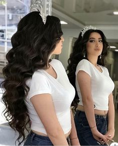 two women in white shirts and jeans are looking at each other with long dark hair