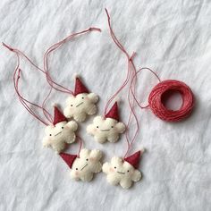 three small white teddy bears with red hats on their heads are hanging from twine