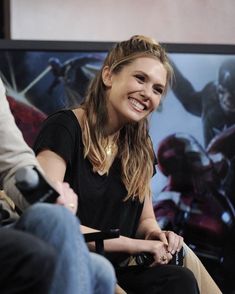 a smiling woman sitting in front of a tv