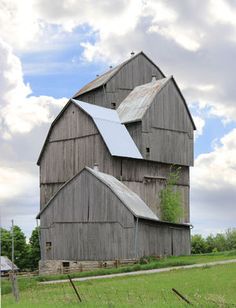 an old barn sits in the middle of a field