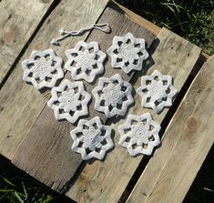 four crocheted snowflakes sitting on top of a wooden pallet