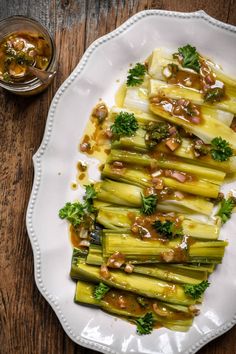 a white plate topped with asparagus covered in sauce and garnished with nuts