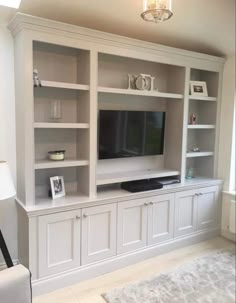 a living room with white bookcases and a flat screen tv