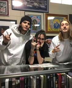 three young men standing in front of a book shelf