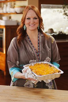 a woman holding a casserole dish in her hands and smiling at the camera