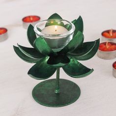 there is a candle that has been placed in a flower shaped holder with candles around it