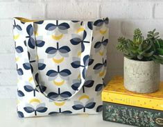 a bag sitting on top of a white table next to a book and plant in a pot