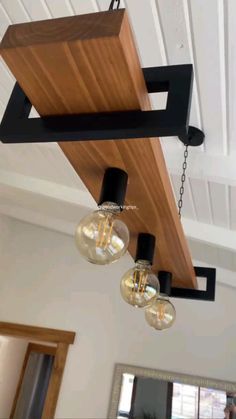 three light fixtures hanging from the ceiling in a room with white walls and wood beams