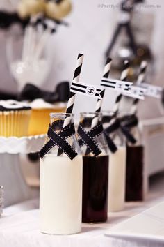 desserts are displayed in glass jars with black and white striped straws on them