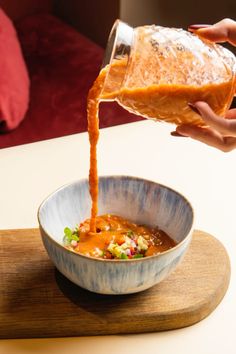 someone is pouring sauce into a bowl with food in it