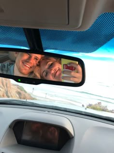 a man and woman taking a selfie in the rear view mirror