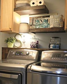 a washer and dryer in a small room with wooden shelves on the wall