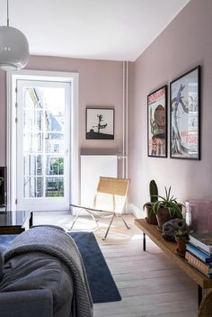 a living room with pink walls and pictures on the wall next to a couch in front of a window