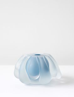 a light blue vase sitting on top of a white table next to a black object