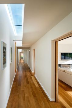 an empty hallway with wood floors and skylights on the ceiling is seen in this image