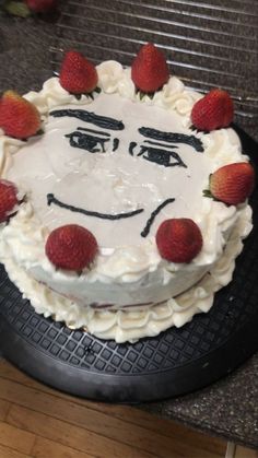 a cake with strawberries on top of it sitting on a counter next to a knife