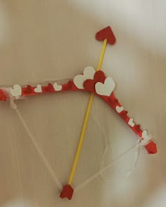 a red and white kite with hearts attached to it's side on a table