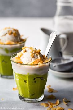 two small cups filled with ice cream and topped with toppings, on top of a table