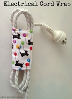 an electric cord wrapped in fabric with cats and balloons on it is plugged into a charger