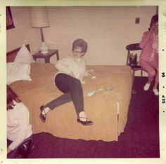 an old photo of a woman sitting on a bed