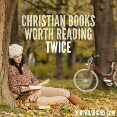 a woman sitting under a tree reading a book