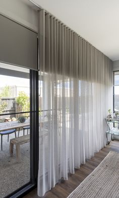 an open living room with sliding glass doors and white drapes on the windowsill