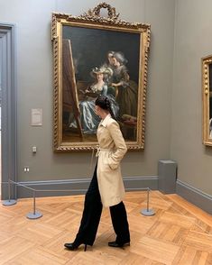 a woman walking through an art museum with paintings on the wall