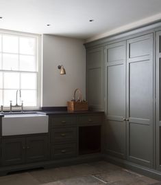 a kitchen with green cabinets and a white sink in the center, along with a large window