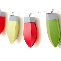 paper christmas lights are hanging on a clothes line with red, green and gray ones