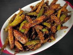 a plate full of fried green beans on a black tablecloth with a red and white border